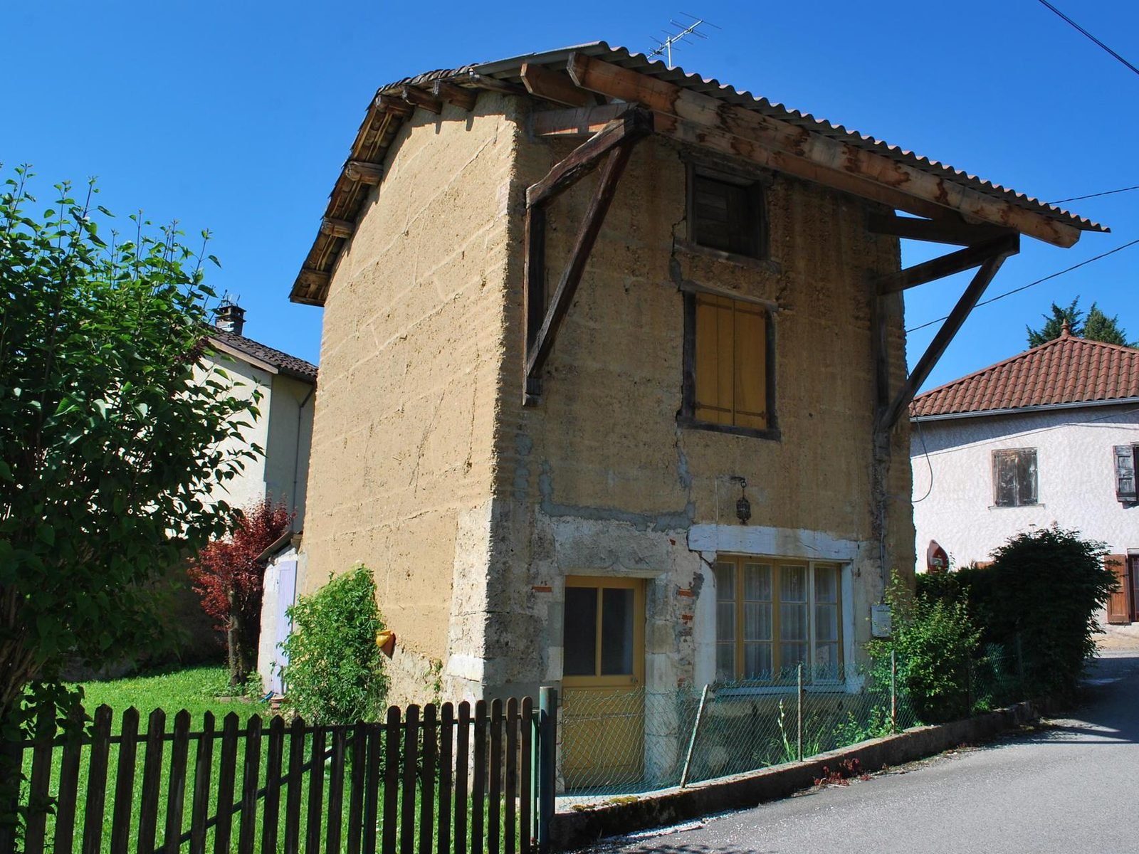 Maison en pisé sous son avant-toit en bois