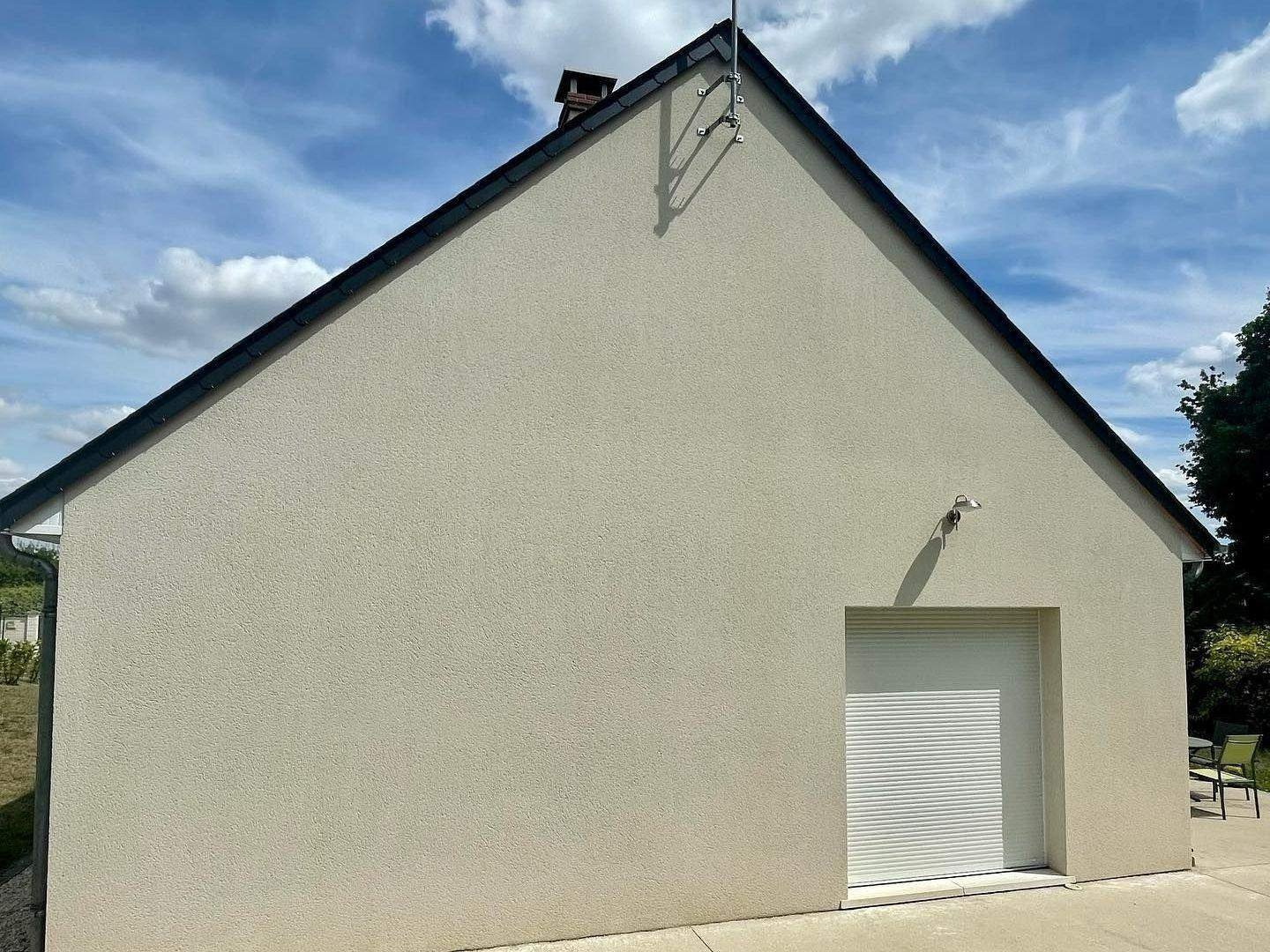 Pignon enduit beige avec porte de garage