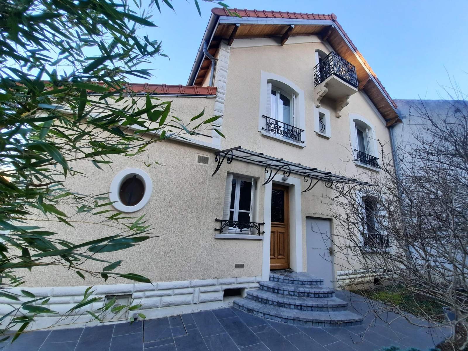 Villa ancienne ravalée en enduit beige, avec oculus et balcon