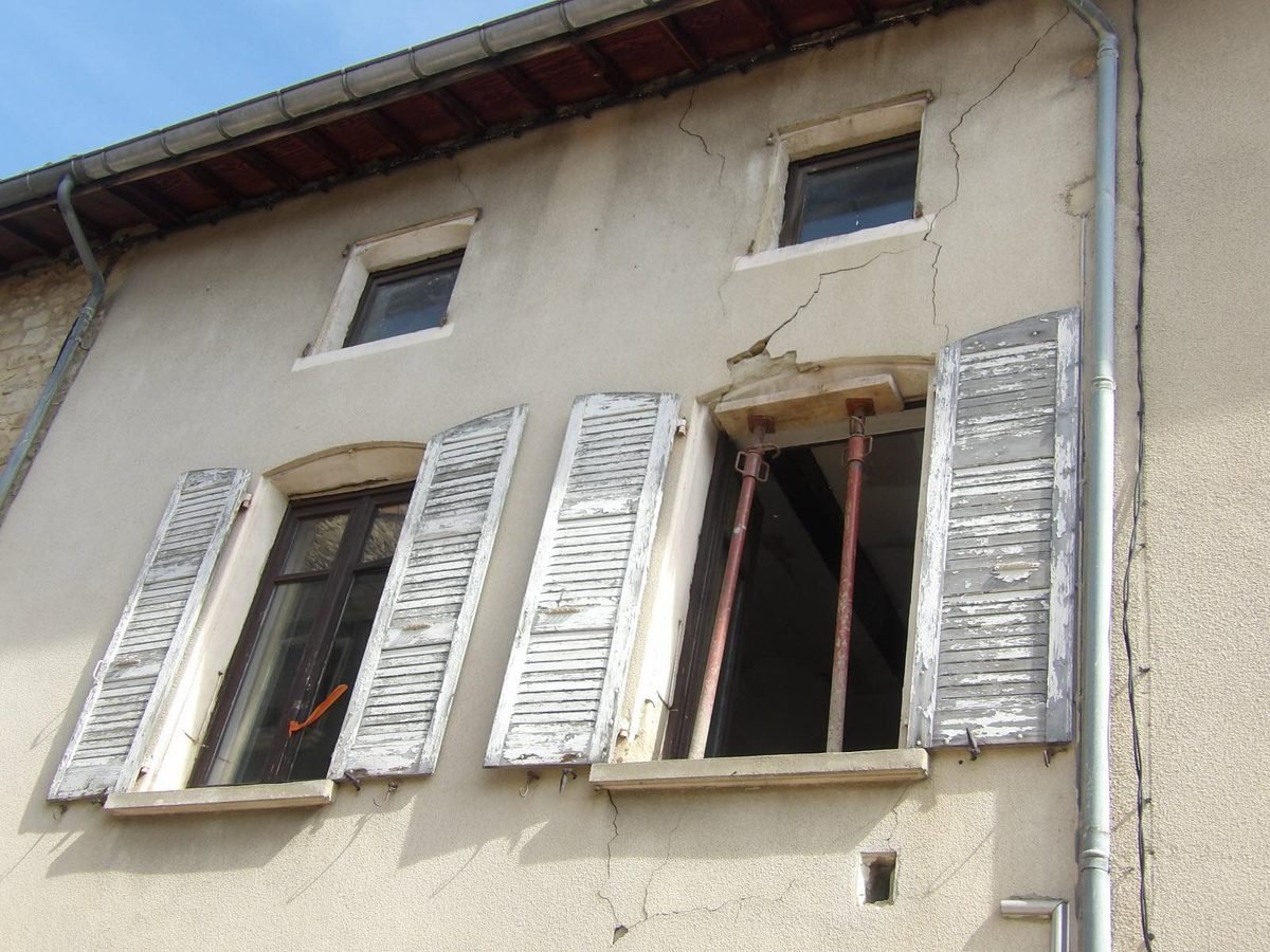 Enduit fissuré sous la toiture d'une maison de bourg