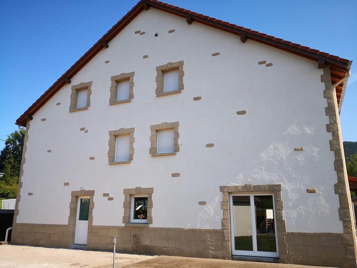 Façade enduite en blanc aux encadrements en pierre