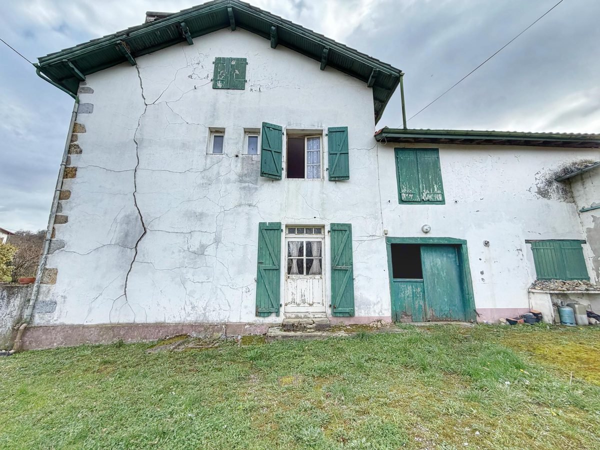 Fissure sur la façade d'une maison aux volets verts