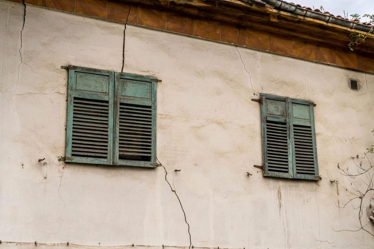 Fissures dans l'enduit sous la génoise d'une maison ancienne
