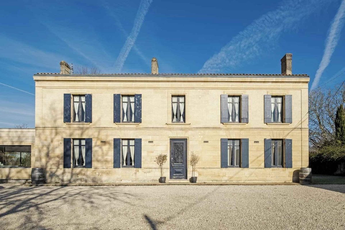 Longue façade en pierre de taille aux volets bleus