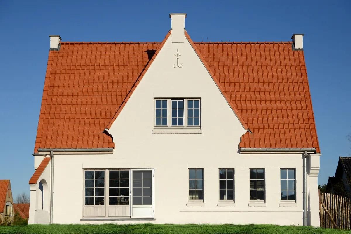 Pignon de maison enduit en blanc sous un toit de tuiles